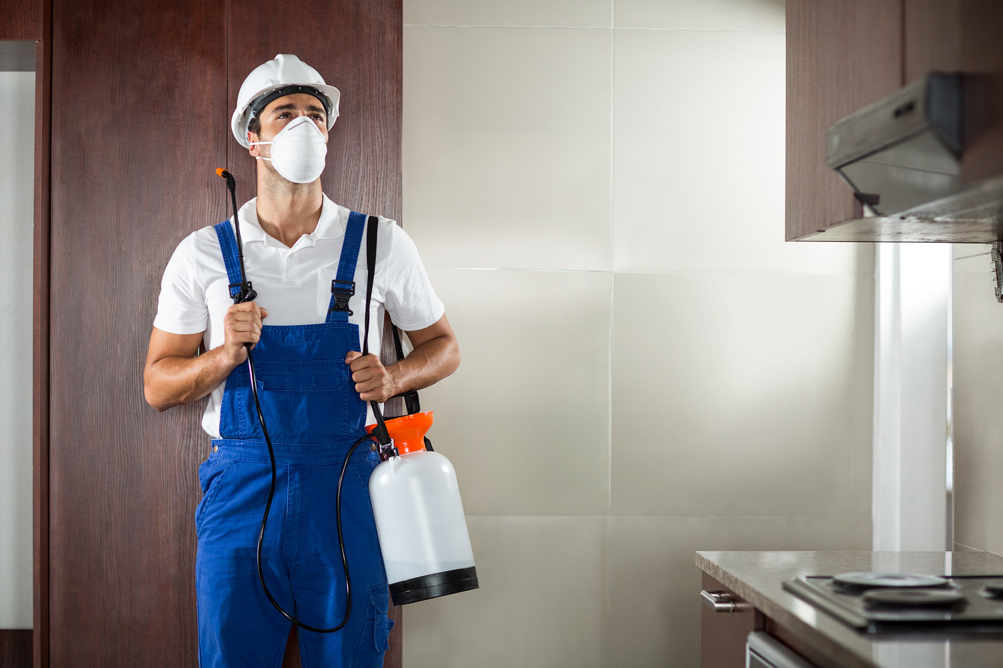 Front view of pest worker spraying standing in kitchen at home